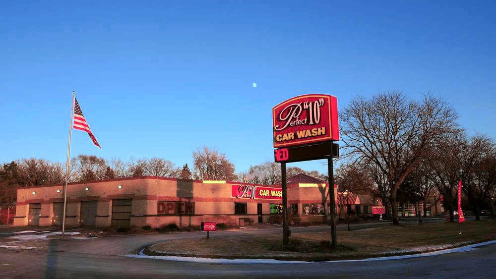The Perfect “10” Car Wash building and its lit sign at dusk