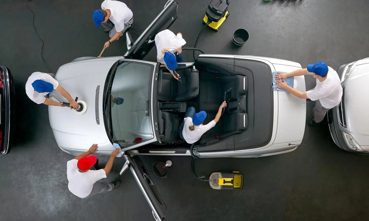 A crew drying and detailing a car by hand after the wash